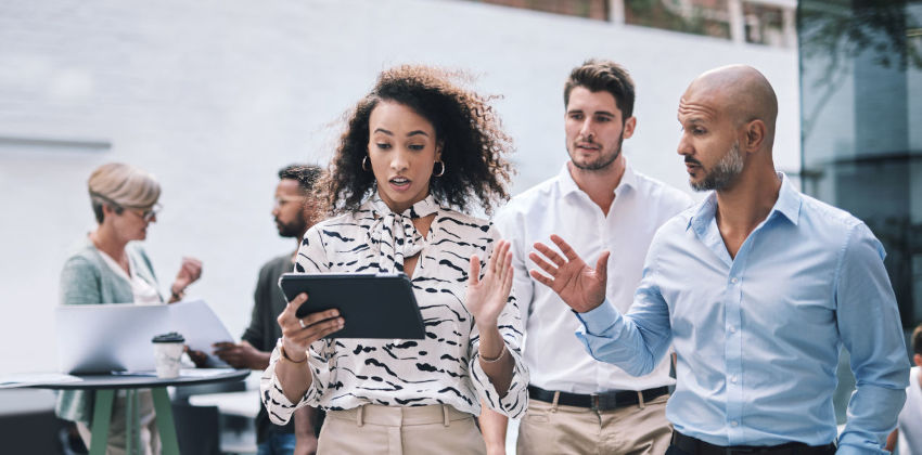 People walking in an office discussing work on a tablet